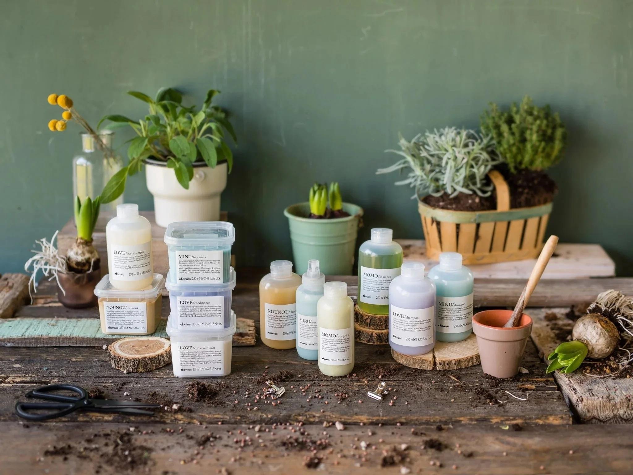 Davines Essential Haircare range arranged on a potting bench with plants and botanical elements